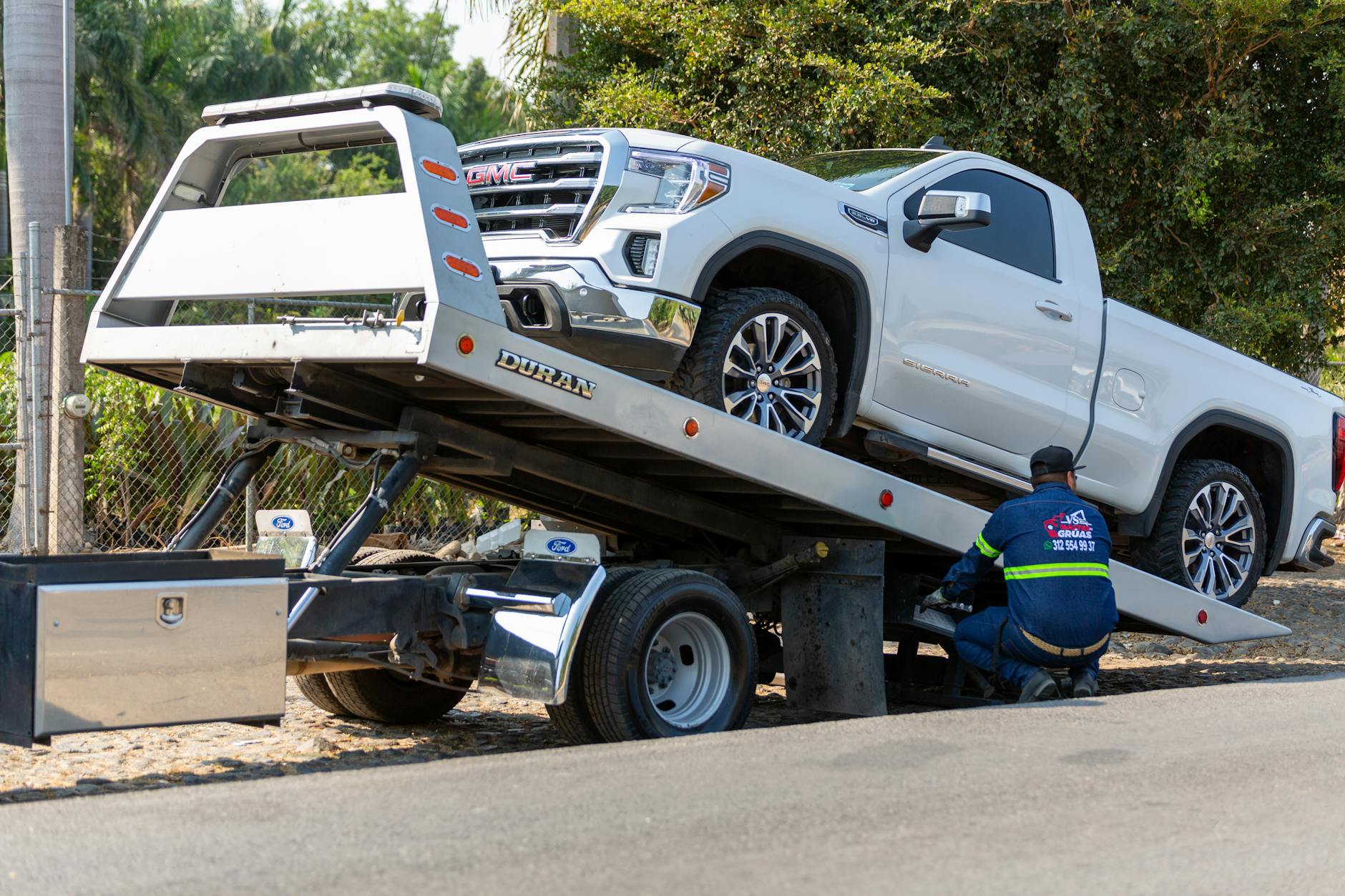 A Slingshot Towing Service operator performing a safety check on a vehicle before transport in Carnuel.